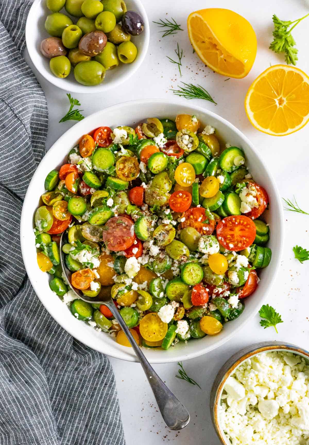 Mediterranean cucumber and tomato salad served in a white bowl topped with feta cheese.