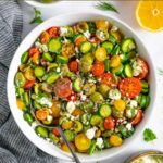 Mediterranean cucumber and tomato salad served in a white bowl topped with feta cheese.