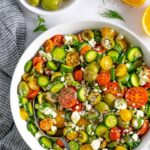 Mediterranean cucumber and tomato salad served in a white bowl topped with feta cheese.