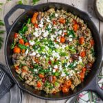 Mediterranean ground chicken stir fry served in a cast iron skillet with a fork next to the skillet.