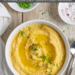 Bowl of mashed rutabaga on a board sprinkled with herbs on a wood board with a spoon.