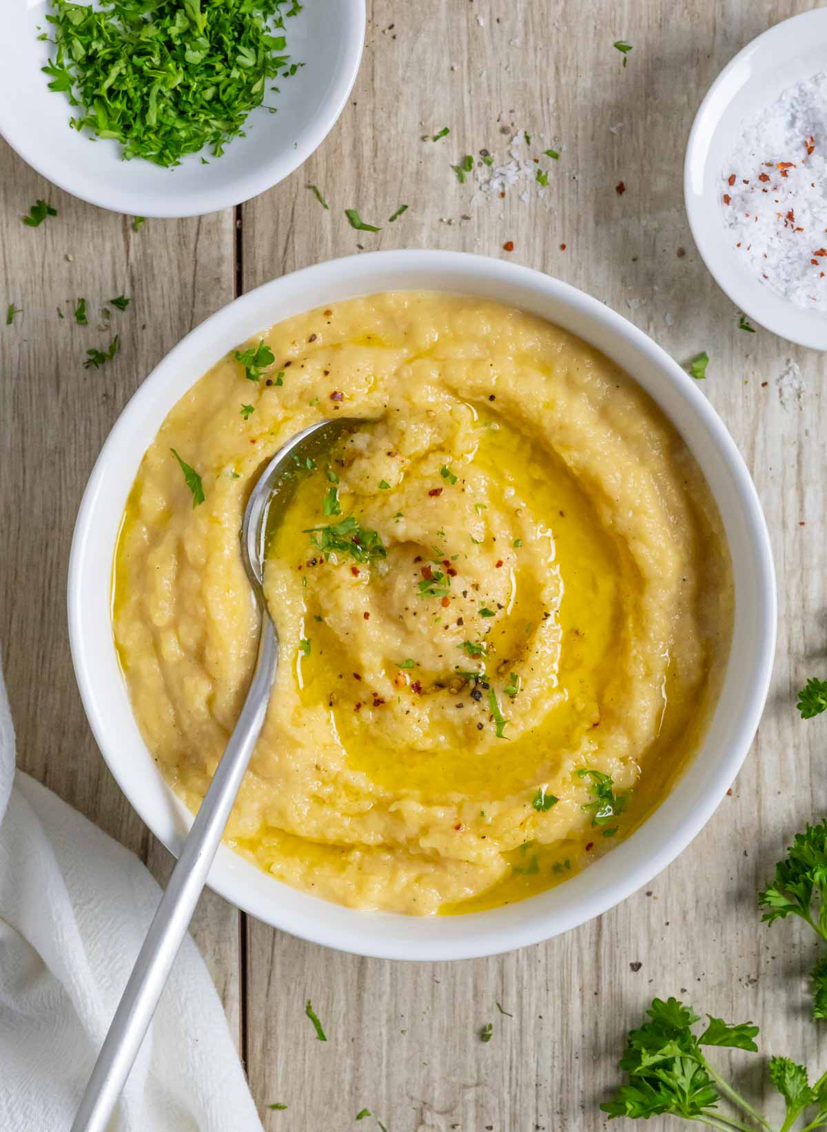 Rutabaga puree in a white bowl with a spoon and sprinkled with herbs.