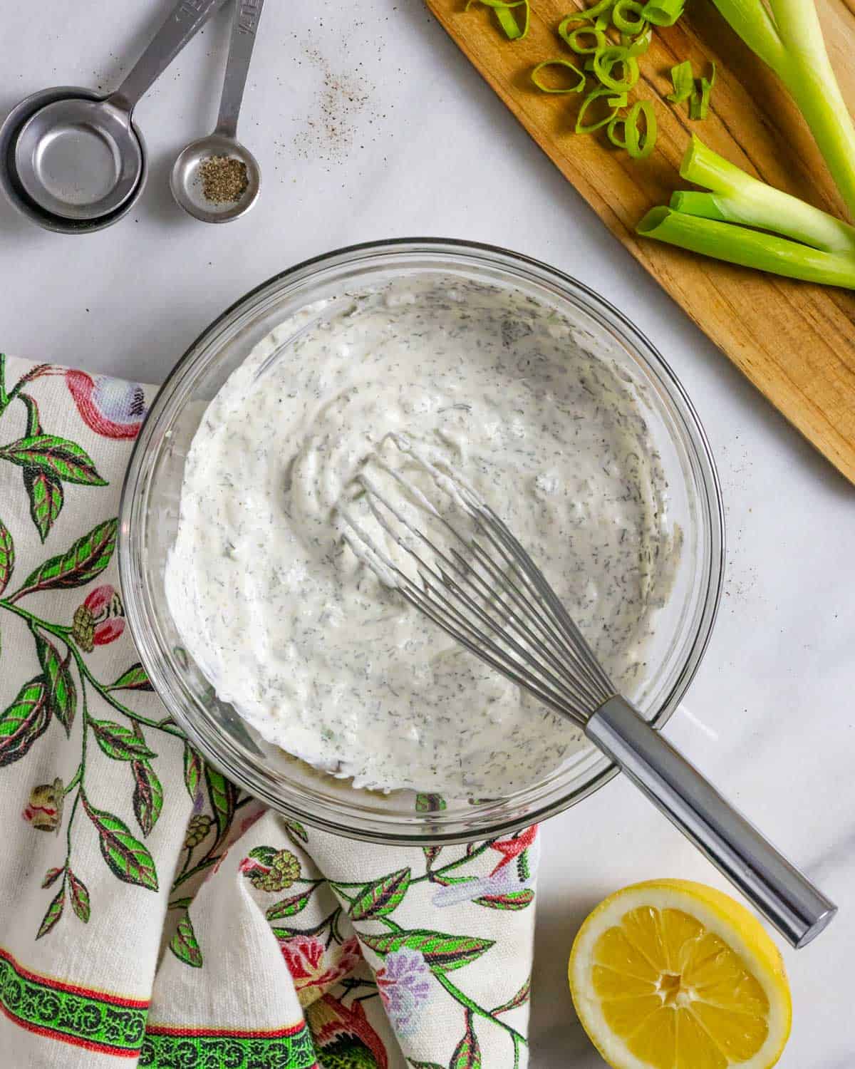 Glass bowl of ranch dressing with a whisk in it, mixed and ready to serve.