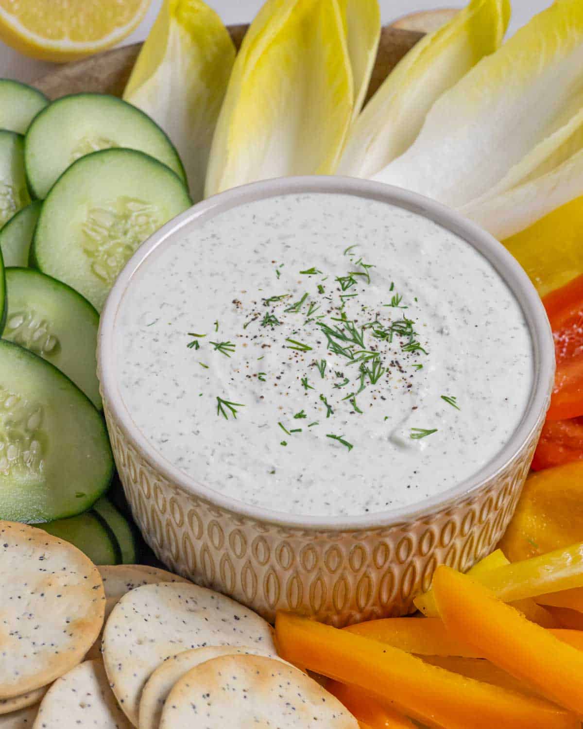 Bowl of whipped cottage cheese dip with ranch dressing surrounded by crackers and veggies on a platter.