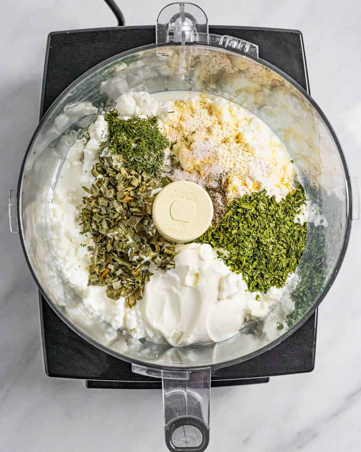 Ingredients for ranch dip unblended in a food processor bowl.