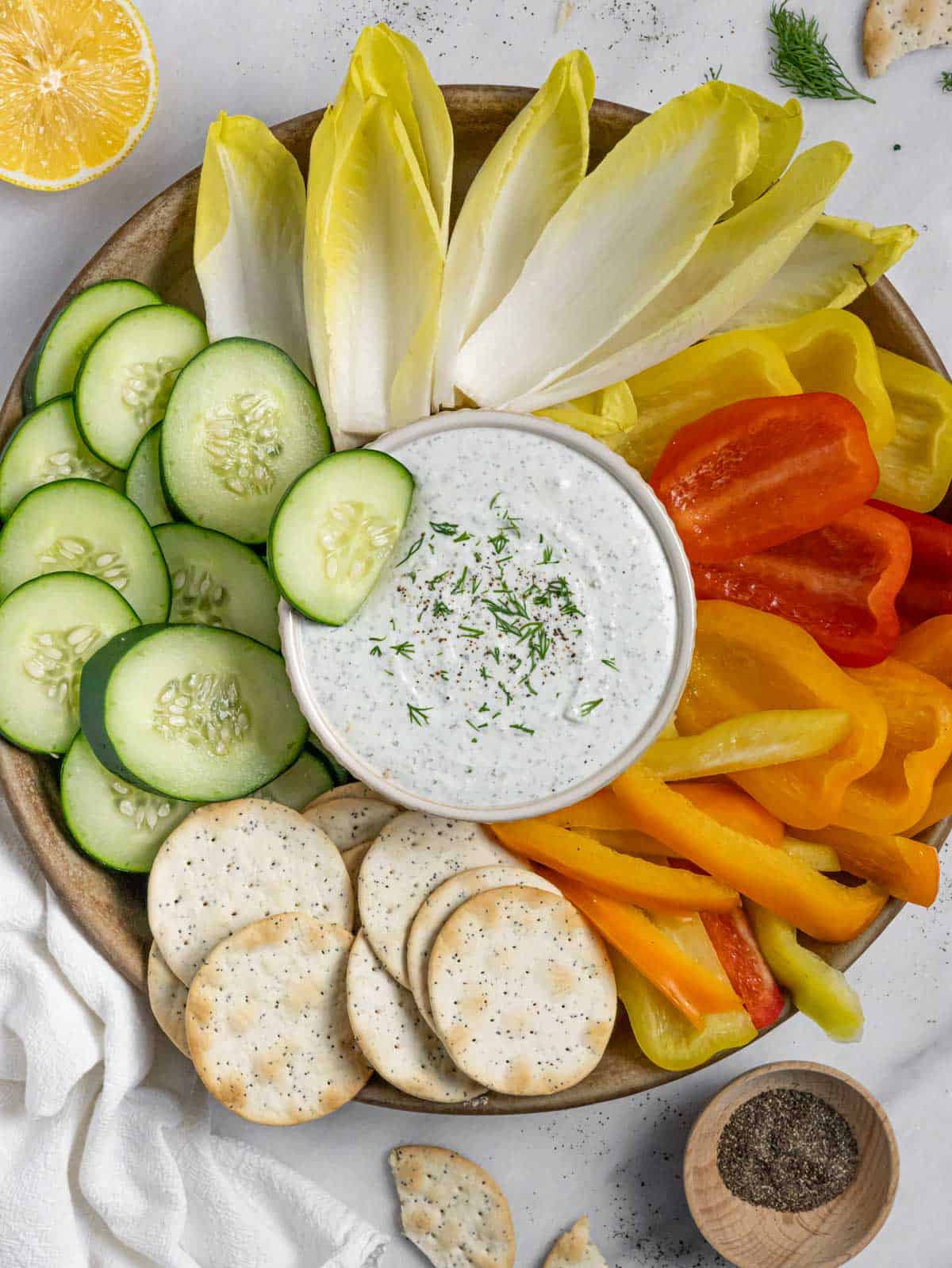Healthy ranch dip with cottage cheese in a bowl on a platter of veggies and crackers.