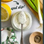 Spoon of ranch dressing balanced over the mouth of a full jar, on a board with spices in small bowls.