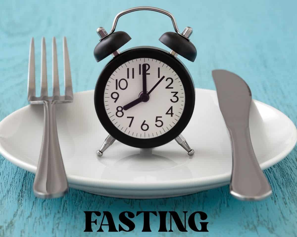 clock on white plate with on blue table with the word fasting underneath