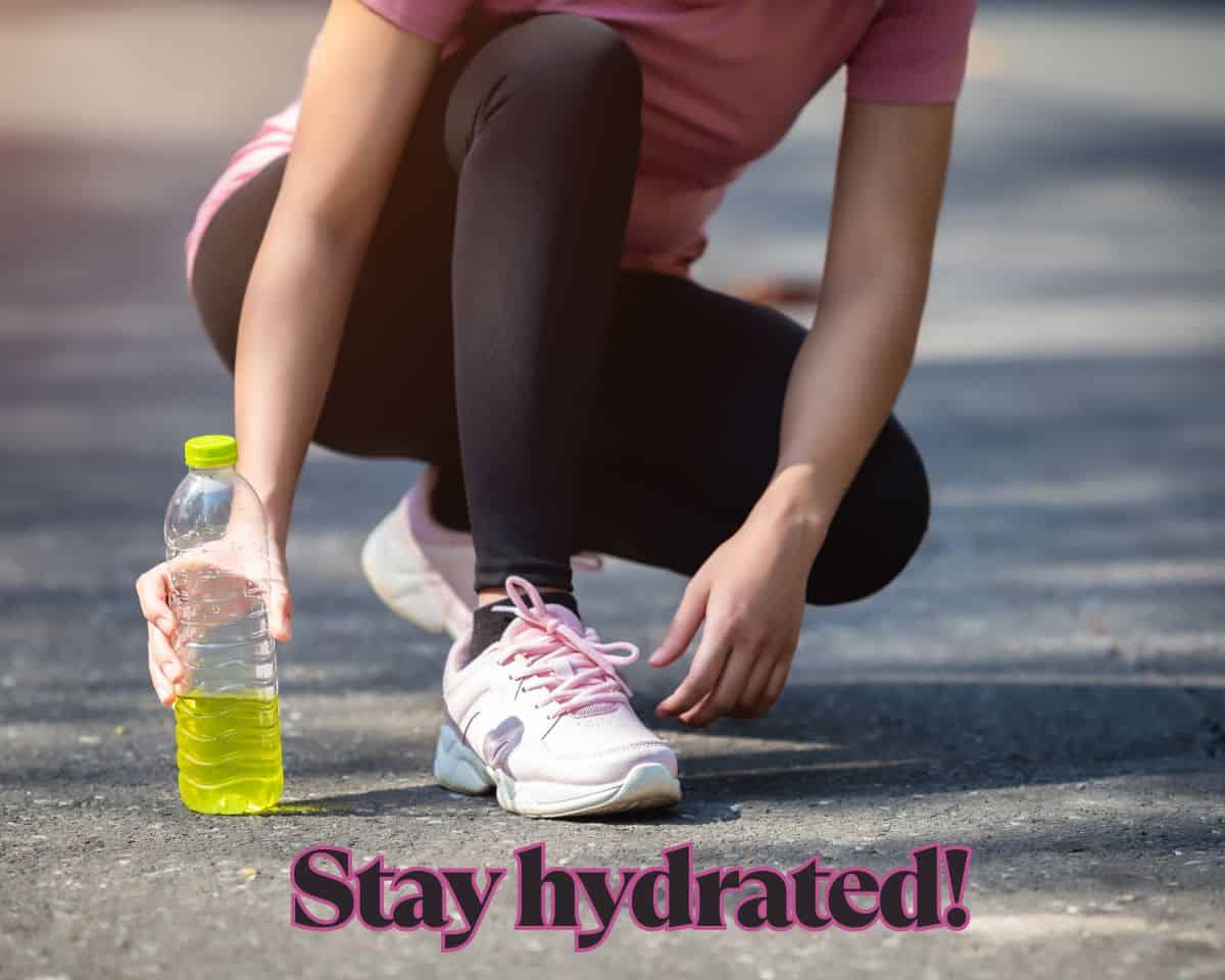 Woman athlete in a lunge grasping a bottle with yellow liquid