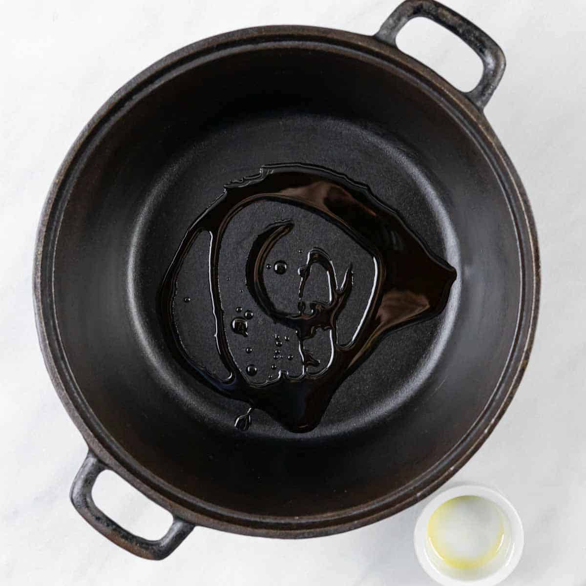 Oil drizzled in a cast iron pot.
