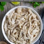 Pulled chicken breast in a white bowl with a fork and napkin on the right side.