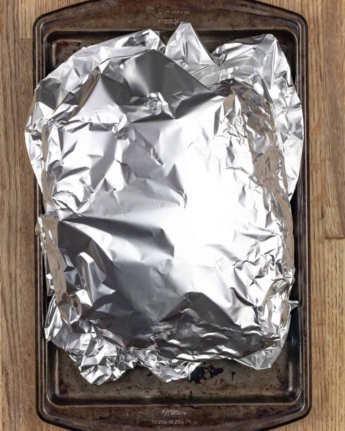Roast resting under foil on a sheet pan